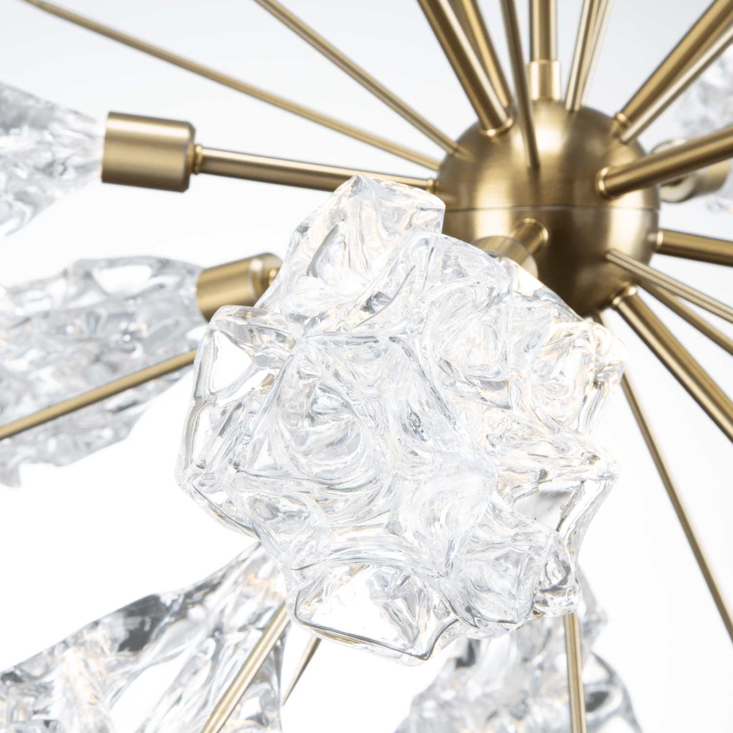 Closup detail of a Hammerton Studio Blossom starburst chandelier with brass finish and blossom-shaped crystal glass light shades.