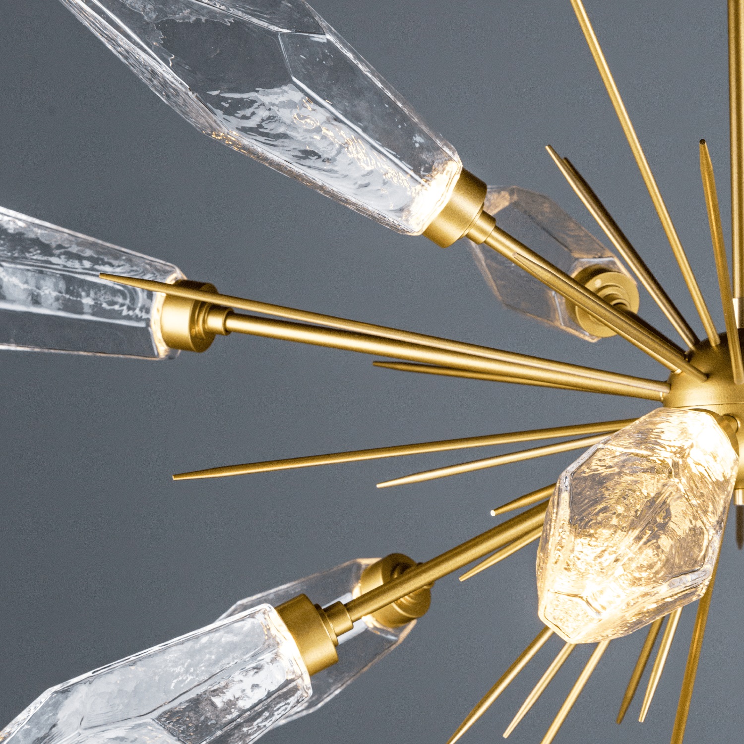 Closeup detail of a Hammerton Studio Rock Crystal starburst chandelier with brass finish and rock crystal-shaped glass light shades.