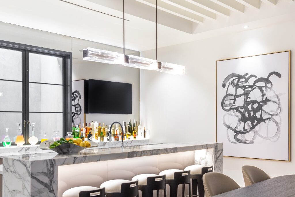 A Hammerton Studio Ledgestone linear suspension hangs above the bar, elongating the space while establishing a welcoming area for family and guests to congregate.