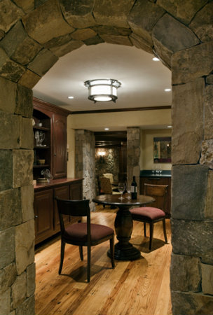  A simple ceiling fixture featuring a simple form and subtle old world details adds a transitional design counterpoint to this cellar's natural stone masonry and rich mahogany. 