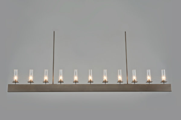  With 11 glass shades and a strong, linear form, this fixture's bold aesthetic is beautifully balanced by a series of small, delicate candles. 