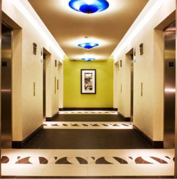  These diminutive yet impactful ceiling fixtures, featuring a vibrant blown Blue Cararra glass, make a bold statement in this hotel elevator lobby. 
