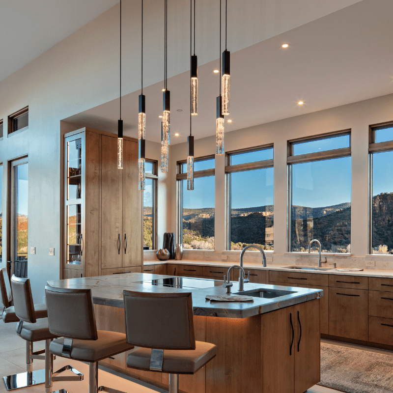 beautiful mountain vistas and sophisticated suspended pendant lighting blend together to make a dramatic kitchen island setting