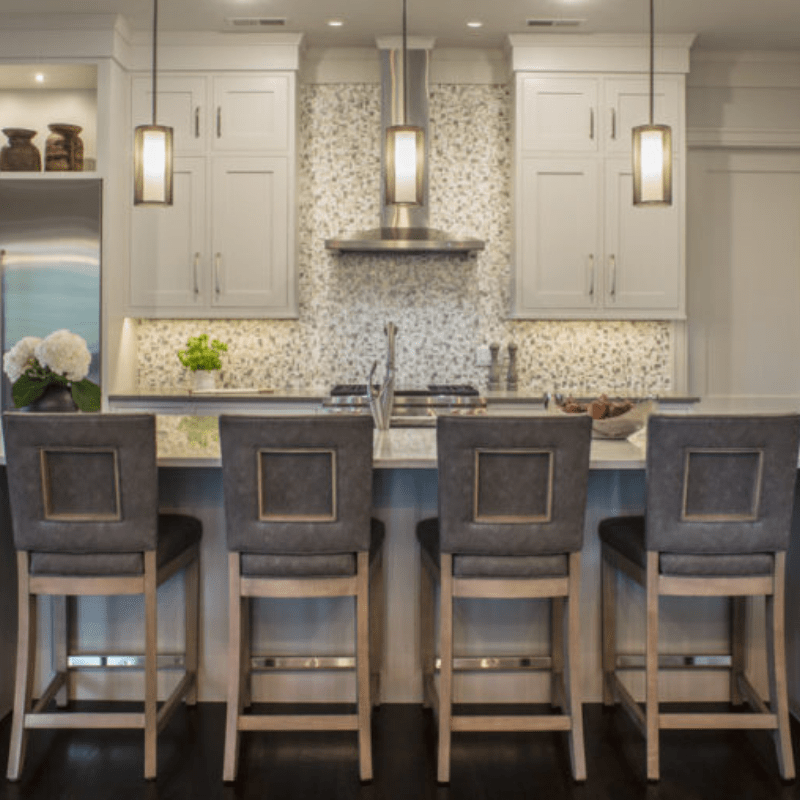 wide kitchen island with four bar stools and three suspended mesh pendant lights above