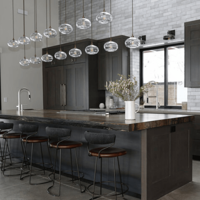 custom multi-bulb pendant chandelier featuring hand blown glass installed over a long kitchen island